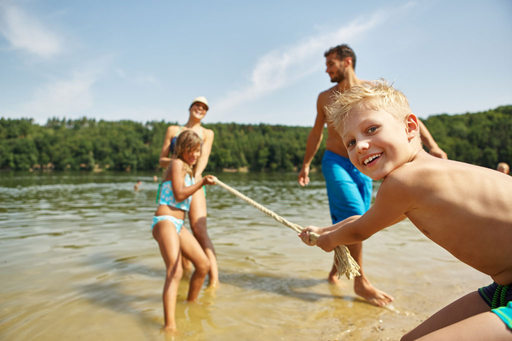 Familie im Sommer beim Tauziehen am See
